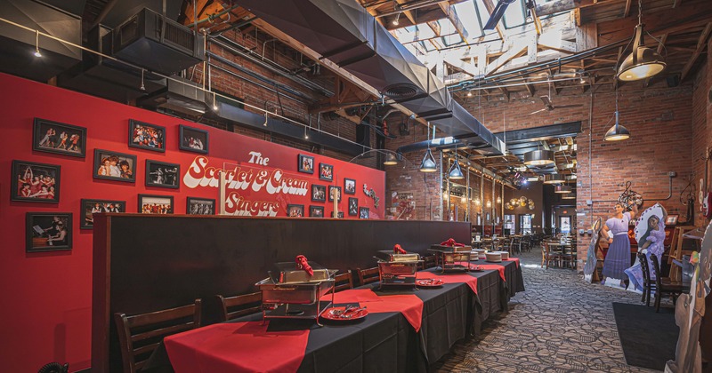 Interior, room with a long buffet table, red wall decorated with framed photos