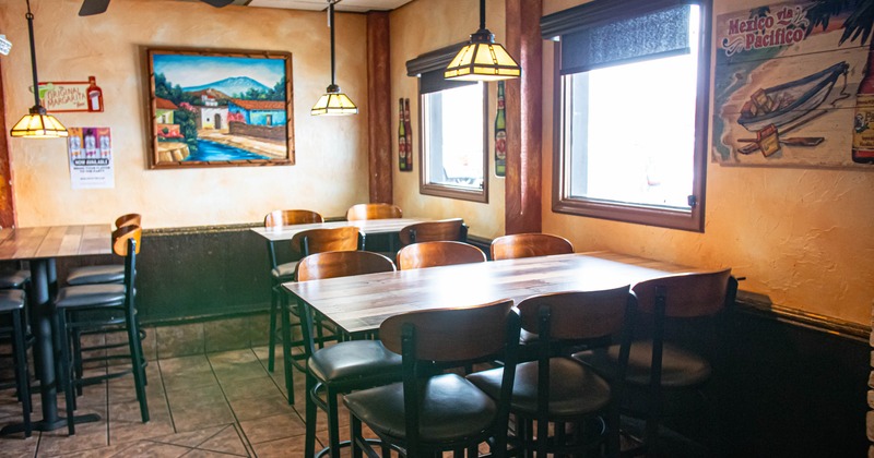 Interior of a cozy restaurant with wooden tables, pendant lights, and wall art