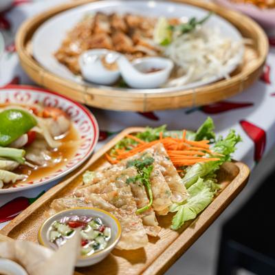 A vibrant spread featuring pan-fried dumplings, papaya salad, and grilled meats.