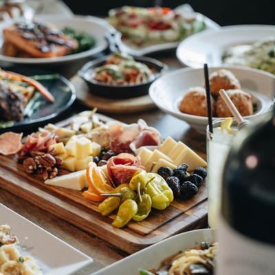 Charcuterie board on a table with surrounding dishes and drinks.