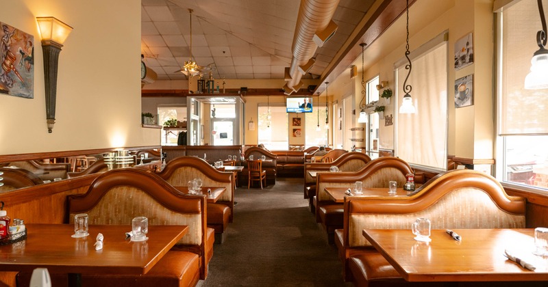 Interior, cozy dining area, wooden seating booths with wooden tables, carpet flooring
