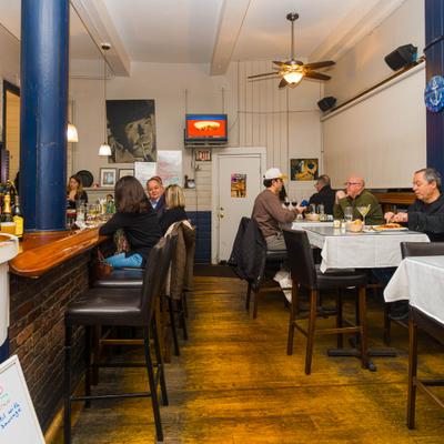 Interior with guests seated at the bar counter and at tables.