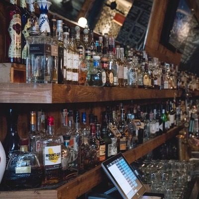 Area behind a bar with liquor bottles, glassware, and a tablet.