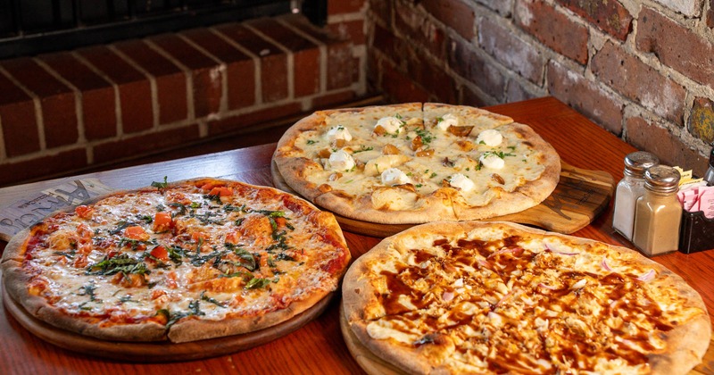 Three pizzas displayed on a wooden table