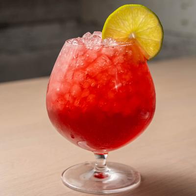 Reggae Radio cocktail drink, red drink garnished with lime wheel.