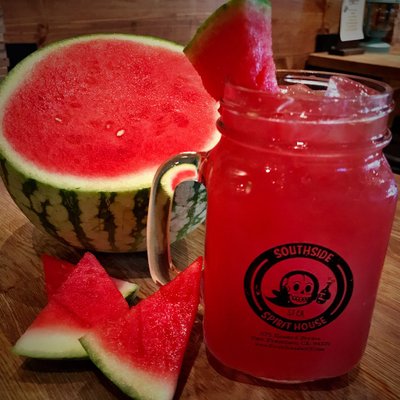Watermelon cocktail with fresh watermelon in the background.