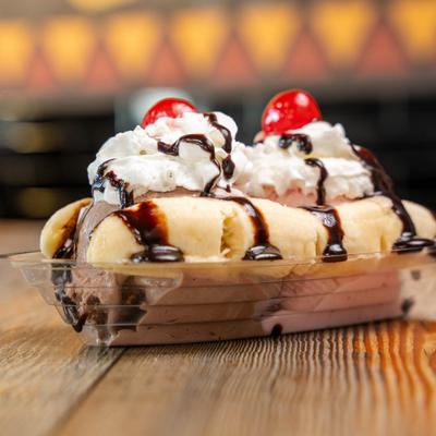 Banana split topped with ice cream, whipped cream. chocolate sauce and cherries.