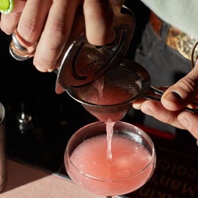 Bartender straining a Bitter French cocktail.