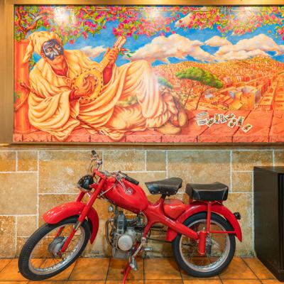 Interior with vintage Italian moped and large, vibrant painting on the wall.