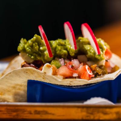 Taco, topped with chipotle, pico de gallo, guacamole, and radish.