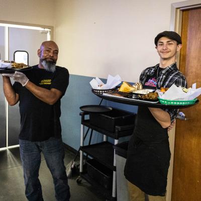 Two staff members holding trays of food.