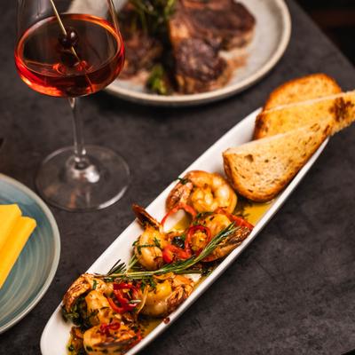 Tiger shrimp with garlic confit and toasted bread, alongside a cocktail.