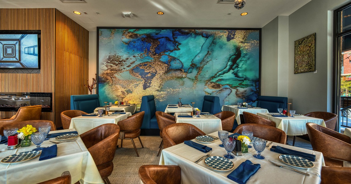 A stylish interior with abstract turquoise mural, set tables and leather chairs.