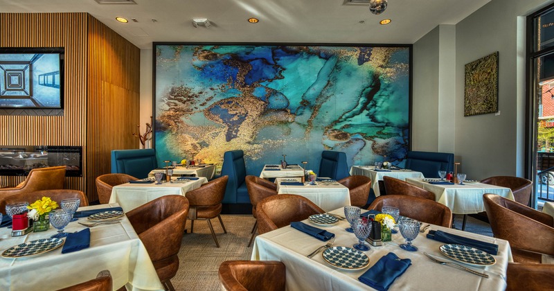 A stylish interior with abstract turquoise mural, set tables and leather chairs.