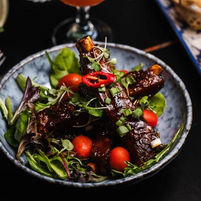 Seasoned pork spare ribs with barbecue sauce, topped with greens and scallions.