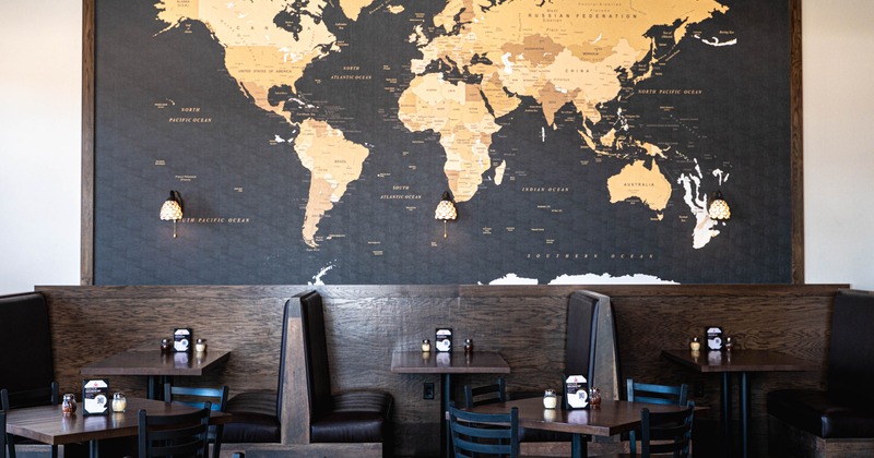 Interior, dining area, booths for two, tables for four, world map wallpaper across the wall