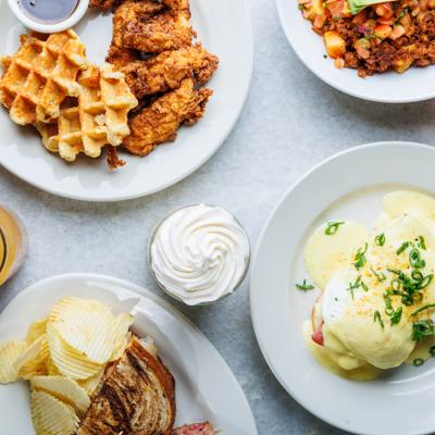Assorted brunch dishes including fried chicken, waffles, eggs Benedict, and toast.