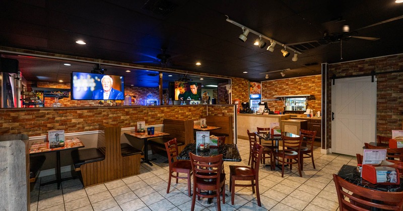 Interior, booth seating area with tables, chairs and TVs on the wall