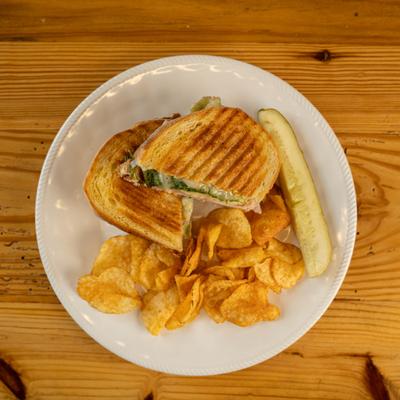 Pilgrim sandwich served with potato chips and a pickle spear on the side.