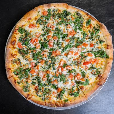 White pizza topped with spinach, tomatoes and mozzarella and provolone cheese.