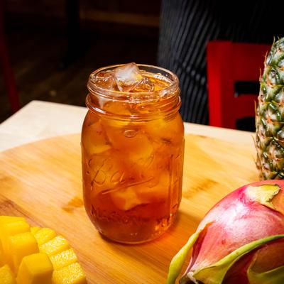 Sweet tea jar with fresh mango, pineapple and dragon fruit on the table