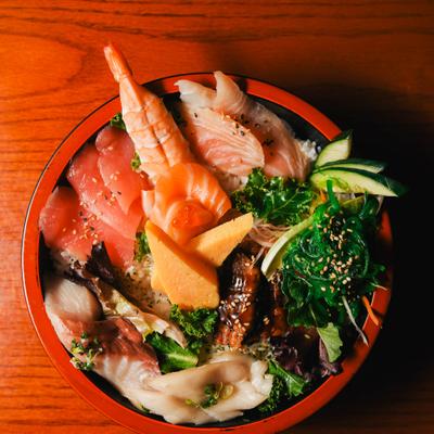 Assortment of fresh sashimi and other ingredients over a bed of sushi rice.