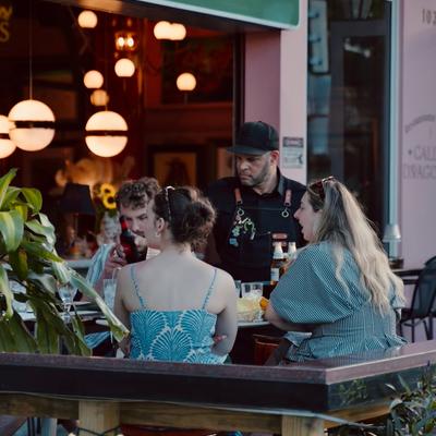 The bartender serving at the terrace to a group of people.