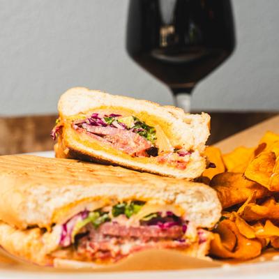 Rockin Reuben Panini and chips with a glass of red wine in the background, close up.