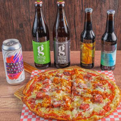 Pizza with mozzarella, cheese curds, parmesan, smoked meat, hot chicken, and beer bottles.
