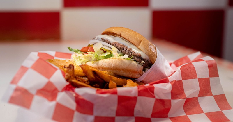 Hamburger served with sweet potato fries in checkered basket