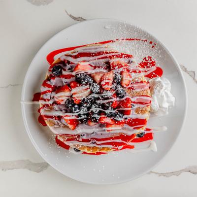 Pancakes topped with berries and serced with whipped cream.