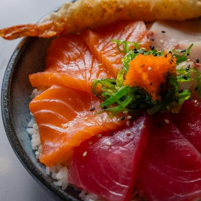Assorted sliced fish and shrimp over rice, garnished with seaweed salad and tobiko.