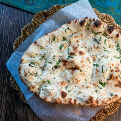 Garlic naan served on parchment over woven basket.