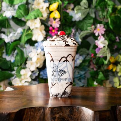 A creamy, chocolate-drizzled milkshake with a cherry on top.