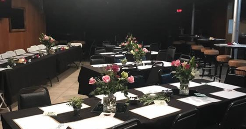 A group of tables with black tablecloths and flowers on it