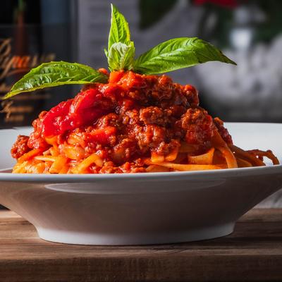 Fettuccine Bolognese with a mint sprig garnish, front view.