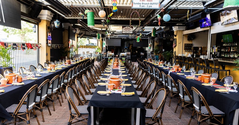 Patio, long rows of tables, orange pitchers, wicker chairs, colorful ceiling decorations