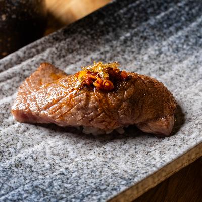 Seared beer nigiri sushi topped with sauce.