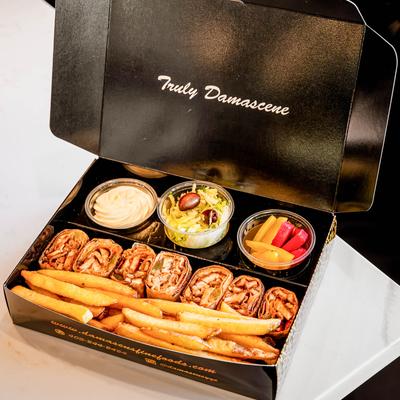 Take out box with chicken shawarma wrap, fries and sides.