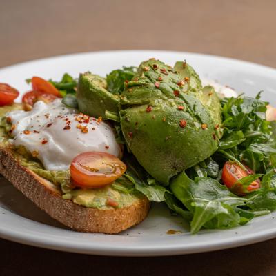 Avocado Toast with poached eggs, arugula and cherry tomatoes.