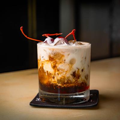 White Russian cocktail garnished with cherries.