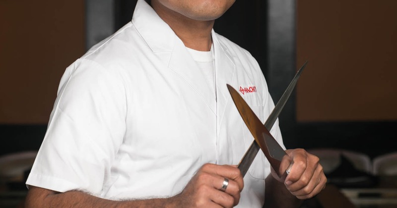 Kitchen employee holding crossed knives