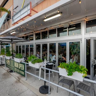 Exterior with signage, outdoor seating, and potted plants.