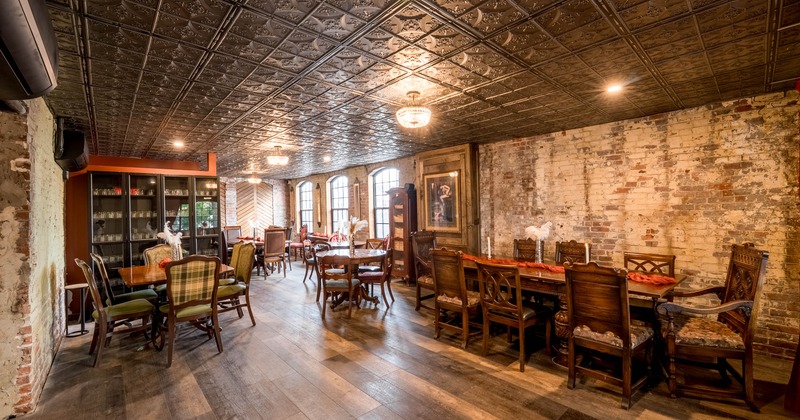 Rustic interior - patterned metallic ceiling, brick walls and various wooden tables and chairs