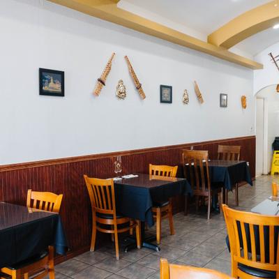 Thai restaurant interior featuring tables, chairs, and bamboo instruments on the wall.