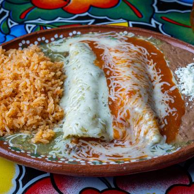 Enchiladas topped with cheese sauce and red sauce, served with refried beans and rice.