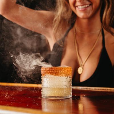 A person preparing a cocktail in a  glass.