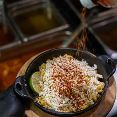 Hand holding Esquites appetizer.