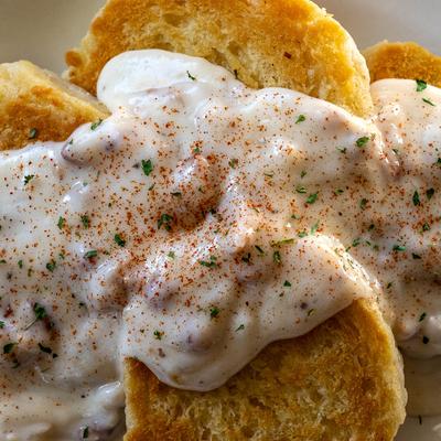 Close up of grilled biscuits covered in country sausage gravy.