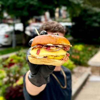 A person holding up a burger to the camera.